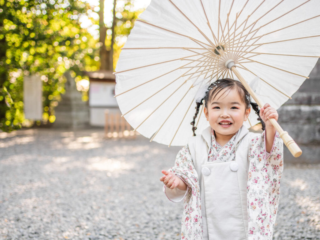 神社で傘を持って笑っている女の子の七五三写真
